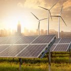 Solar Panels And Windmills With City Skyline In Background