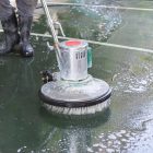 Person Cleaning Floor With Industrial Scrubber